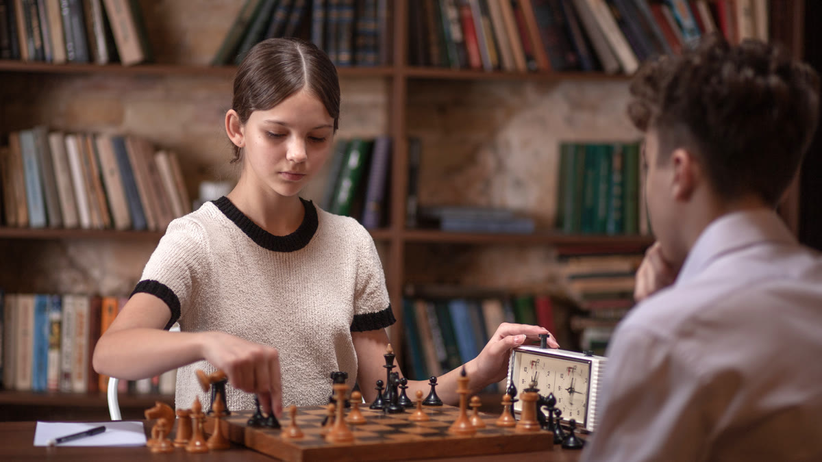 Two young people practicing strategy and focused thinking over a chessboard