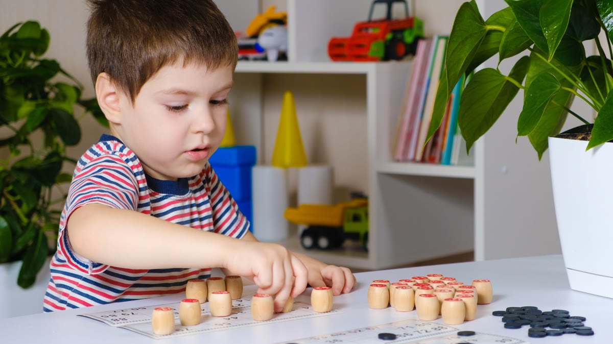 Young child using a hands-on number game at a table at home