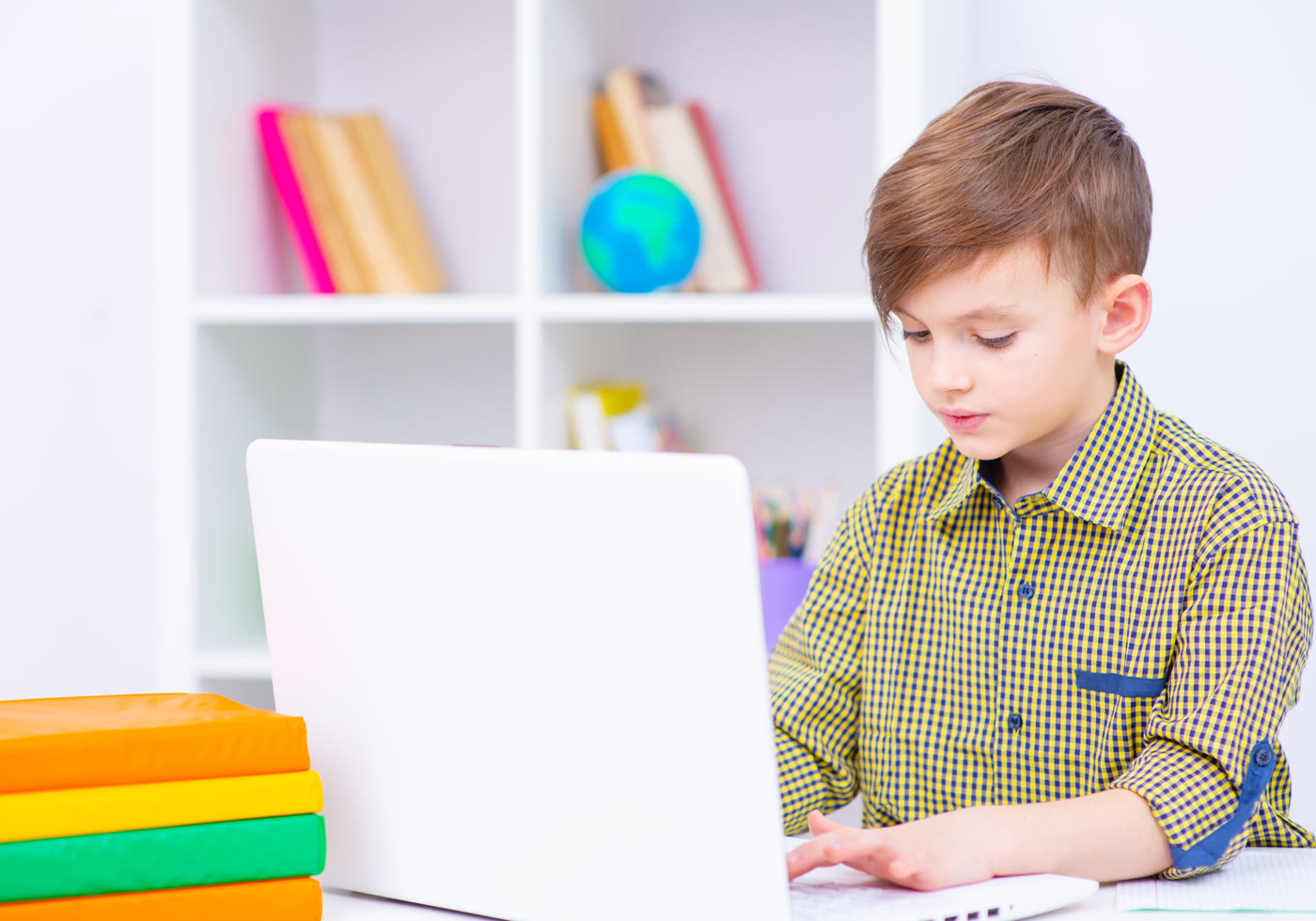 Child using a laptop for a focused learning activity at home