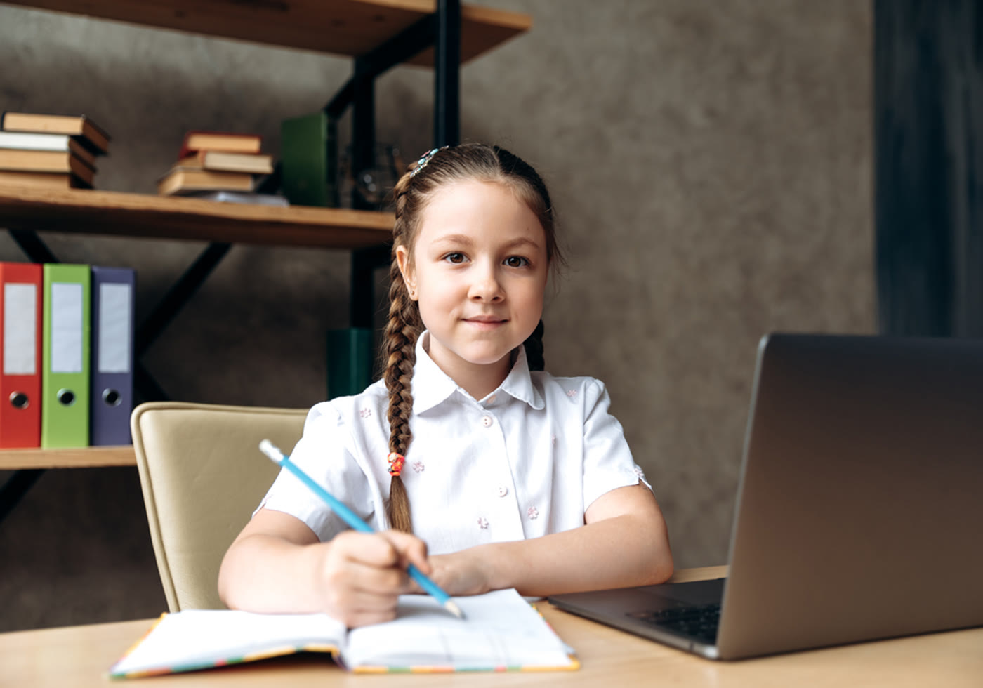 Child working independently with a notebook and laptop in an organized learning space