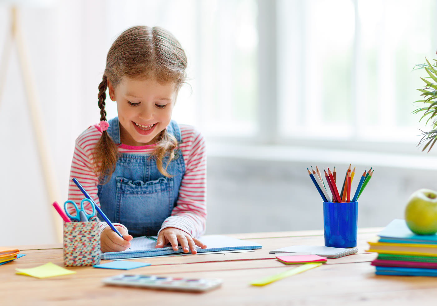 Child writing independently at a bright home learning table